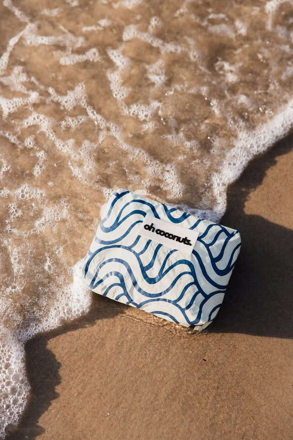 blue wet dry bag laying on beach with wave 
