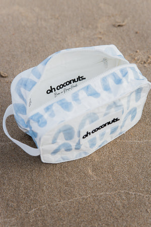 white and blue cosmetic bag on the beach. 
