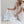 model in linen dress holding white and blue duffel bag and cosmetic bag