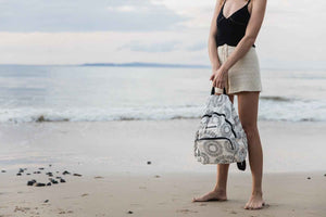 model holding the nixon backpack on the beach 