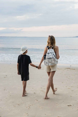model walking with a child on beach with oh coconuts backpack