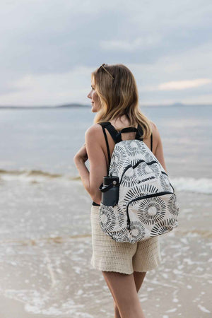 Model walking along little cove beach with backpack 