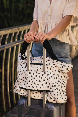 coco beach bag slid over a carry on suitcase 