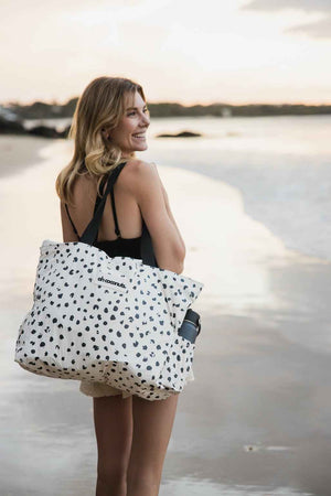 model holding coco beach bag at sunset at little cove beach