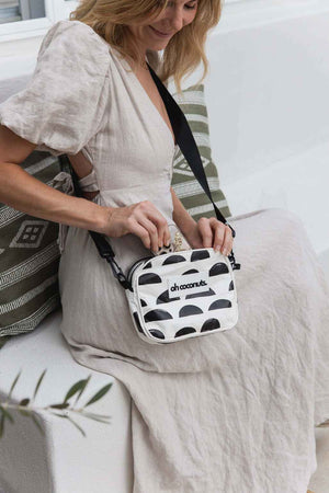 black and cream crossbody bag with black strap on model in linen dress