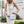 Model in white dress holding blue and white crossbody bag with white strap