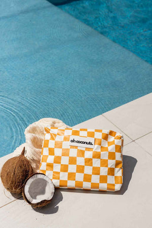 mustard and white checkered bag by pool with coconuts. 