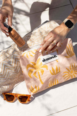 model holding wet dry bag with towel and sunglasses