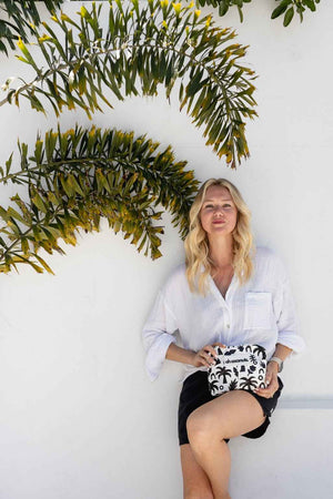 Model holding black and white palm tree print on white wall with palm tree