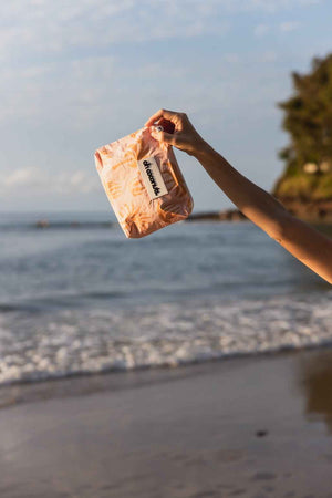 model on beach holding pink oh coconuts palm tree print bag