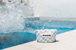 water splashing from pool onto white and blue checkered bag
